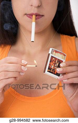 若い女性 タバコをつけること で A マッチ ストックイメージ