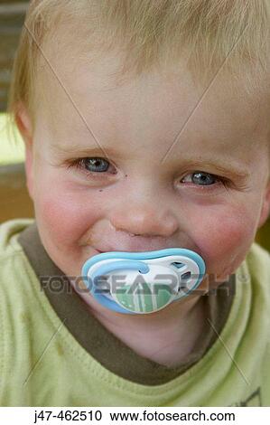 1 year old baby boy smiling cheekily into camera, outside on a sunny day, with a dummy in his mouth View Large Photo Image Stock Image - 1 year old baby boy smiling cheekily into camera, outside on a sunny day, with a dummy in his mouth. Fotosearch