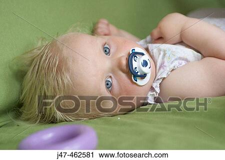 1 year old girl lying on her back sucking a dummy, looking into camera View Large Photo Image Stock Image - 1 year old girl lying on her back sucking a dummy, looking into camera. Fotosearch
