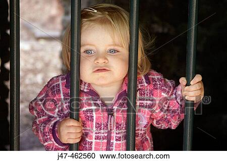 1 year old girl stanging behind some bars, looking miserable View Large Photo Image Stock Image - 1 year old girl stanging behind some bars, looking miserable. Fotosearch
