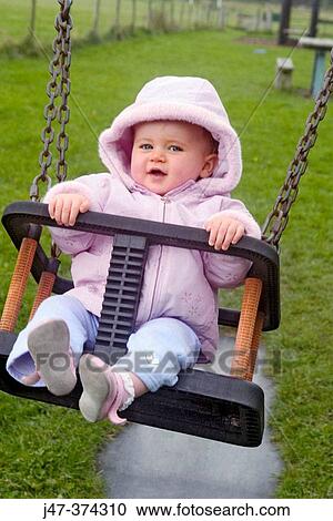 10 Month Old Baby Girl Swinging In Park Smiling Stock Image