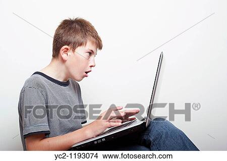 10 year old boy looking shocked while viewing his laptop computer in the studio View Large Photo Image Picture - 10 year old boy looking shocked while viewing his laptop computer in the studio. Fotosearch