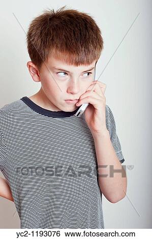 Stock Photograph - 10 year old boy talking on the phone in the studio and looking angry. Fotosearch