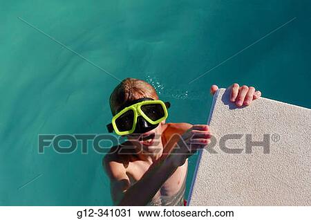 Stock Image - 10 year old boy wearing goggles in swimming pool. Fotosearch