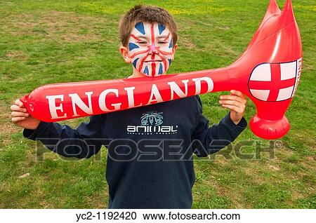 Stock Image - 10 year old boy with his face painted as an England union jack flag holding an inflatable hammer in the Uk. Fotosearch