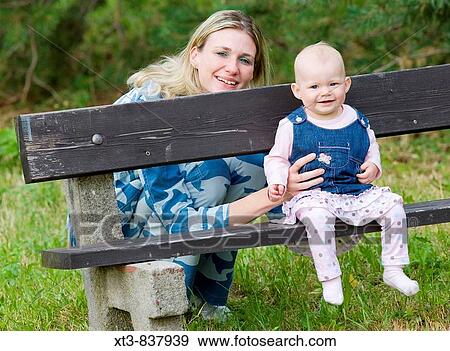 11 months old baby girl with her mother sitting on a bench View Large Photo Image Stock Photo - 11 months old baby girl with her mother sitting on a bench. Fotosearch
