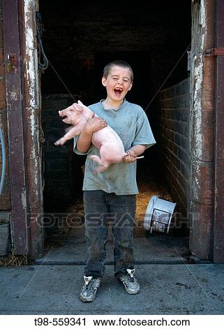 Stock Image - 11 year old boy and pigglet on Scottish farm. Fotosearch