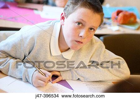 12 year old boy, sitting in class, concentrating, drawing looking into camera, serious View Large Photo Image Picture - 12 year old boy, sitting in class, concentrating, drawing looking into camera, serious. Fotosearch