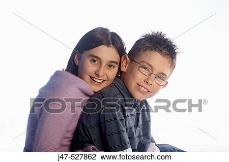Stock Image - 12 year old girl sitting with her 8 year old brother, smiling into camera. Fotosearch