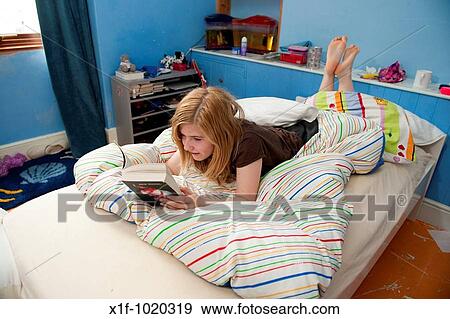 14 year old Teenage girl reading a book lying on the bed in her bedroom View Large Photo Image Stock Photo - 14 year old Teenage girl reading a book lying on the bed in her bedroom. Fotosearch