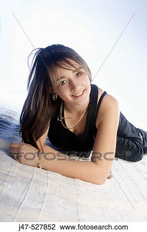 Stock Image - 15 year old lying on her tummy, smiling into camera. Fotosearch
