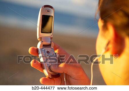 Stock Photo - 16 years old teenager listening to music in a MP3 mobile phone. Hendaye beach. Aquitaine. France.. Fotosearch