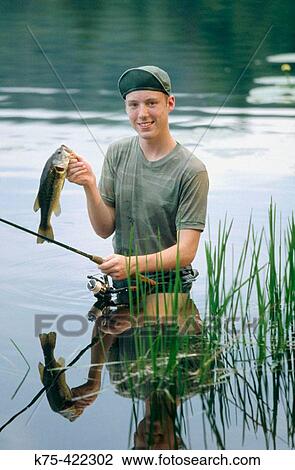 Stock Image - 17 years old boy with Largemouth Bass. Fotosearch