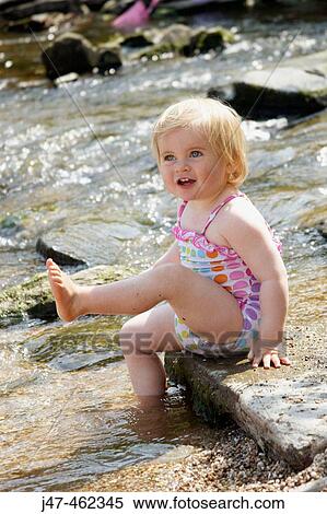 18 month old baby girl, sitting on a stone in a river kicking her foot in the air, smiling View Large Photo Image Stock Photography - 18 month old baby girl, sitting on a stone in a river kicking her foot in the air, smiling. Fotosearch