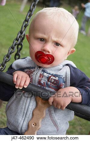 18 month old boy sitting in a swing with a dummy, scouling into camera View Large Photo Image Stock Image - 18 month old boy sitting in a swing with a dummy, scouling into camera. Fotosearch