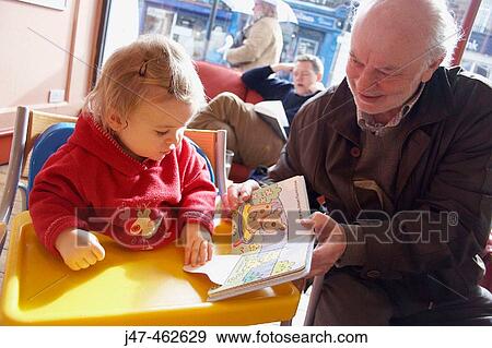 18 month old girl in a cafe looking at a book with her grandad View Large Photo Image Stock Photo - 18 month old girl in a cafe looking at a book with her grandad. Fotosearch