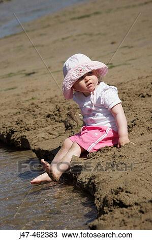 18 month old girl sitting on the beach paddling her feet in the water View Large Photo Image Stock Image - 18 month old girl sitting on the beach paddling her feet in the water. Fotosearch