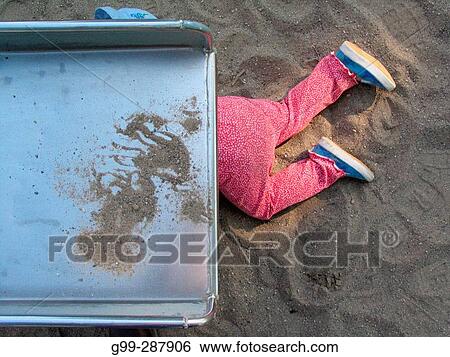 Stock Photograph - 18 month old toddler playing under slide at playground. Fotosearch