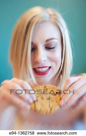 Stock Photo - 19 year old blond woman holding a chocolate cookie. Fotosearch