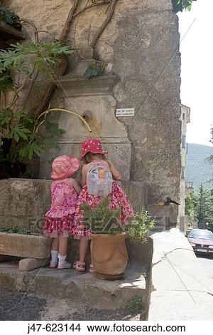 2 and 4 year old sisters, standing at a well, backs to camera, Provence, France. View Large Photo Image Picture - 2 and 4 year old sisters, standing at a well, backs to camera, Provence, France.. Fotosearch