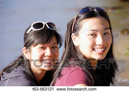 2 asian girls sitting together on beach View Large Photo Image Stock Image - 2 asian girls sitting together on beach. Fotosearch
