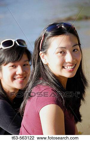 2 asian girls sitting together on beach View Large Photo Image Stock Image - 2 asian girls sitting together on beach. Fotosearch