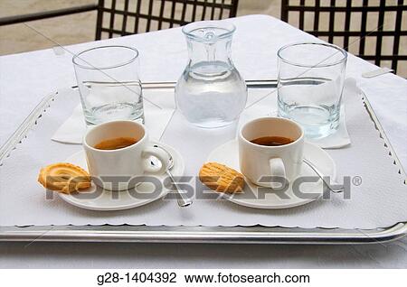 Stock Image - 2 cups of coffee with biscuits, and 2 glasses of water on a tray. Fotosearch