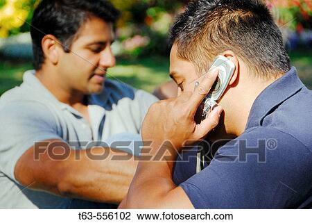 2 ethnic male adults- one on cell phone View Large Photo Image Stock Image - 2 ethnic male adults- one on cell phone. Fotosearch