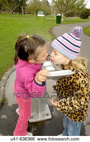 2 friends sharing a drink from the fountain in the park View Large Photo Image Stock Photograph - 2 friends sharing a drink from the fountain in the park. Fotosearch