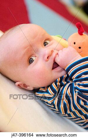 2 month old baby boy, lying on the floor serious, hand in mouth View Large Photo Image Picture - 2 month old baby boy, lying on the floor serious, hand in mouth. Fotosearch