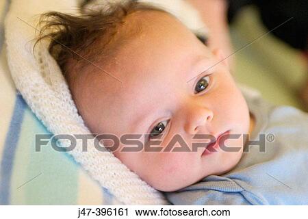 Stock Image - 2 month old baby boy, lying on the floor serious. Fotosearch