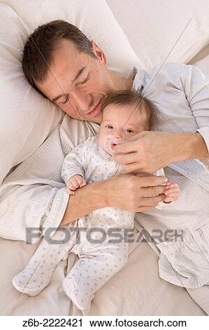 2 months baby lying in bed with her dad. both in pyjamas. View Large Photo Image Stock Image - 2 months baby lying in bed with her dad. both in pyjamas.. Fotosearch