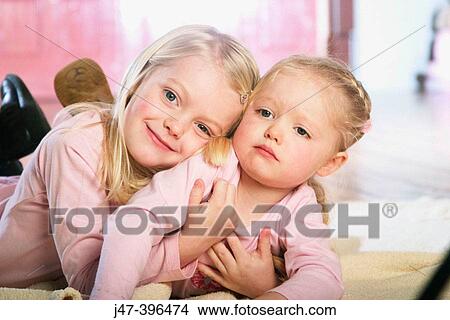 2 sisters, 5 and 3, lying on the floor cuddling View Large Photo Image Picture - 2 sisters, 5 and 3, lying on the floor cuddling. Fotosearch
