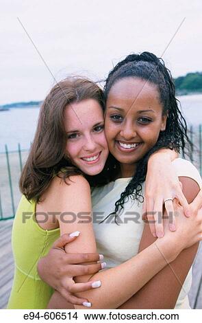 2 teenage girls (one black, one white) hugging each other, smiling and looking at the camera View Large Photo Image Picture - 2 teenage girls (one black, one white) hugging each other, smiling and looking at the camera. Fotosearch
