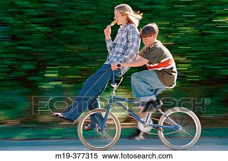 Stock Photography - 2 teenagers on a bike eating ice cream. Fotosearch