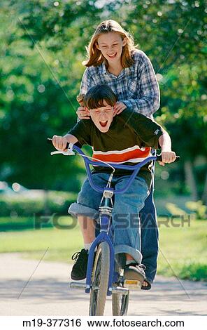 Stock Photograph - 2 teenagers on a bike. Fotosearch