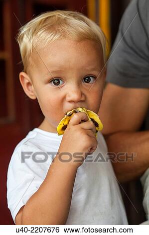 Stock Photograph - 2 Year old boy eating banana.. Fotosearch