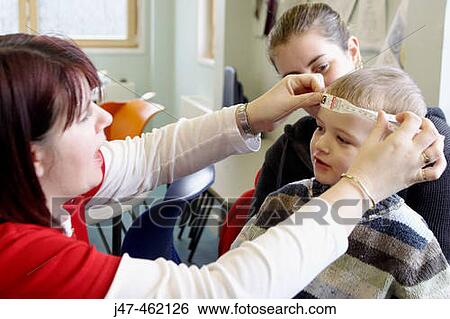 Stock Photograph - 2 year old boy having his head measured by the health visitor. Fotosearch