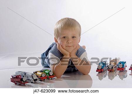 2 year old boy lying on his tummy surrounded by his trains, in the studio View Large Photo Image Stock Photo - 2 year old boy lying on his tummy surrounded by his trains, in the studio. Fotosearch