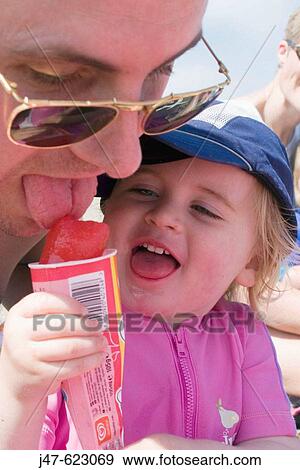 Stock Photo - 2 year old girl, sharing her ice lolly with her daddy. Fotosearch