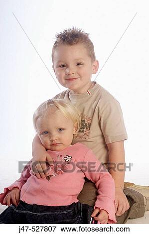 2 year old girl sitting with her 4 year old brother, in the studio, smiling into camera View Large Photo Image Stock Photo - 2 year old girl sitting with her 4 year old brother, in the studio, smiling into camera. Fotosearch