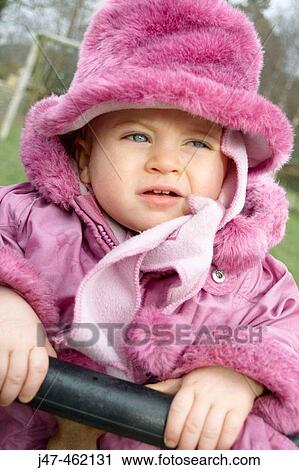 Stock Image - 20 month olg girl sitting in a swing. Fotosearch