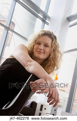 Stock Photograph - 20 year old girl sitting on a chair, smiling into camera. Fotosearch