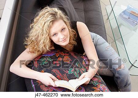 20 year old girl sitting on the sofa, smiling into camera, with a book View Large Photo Image Stock Image - 20 year old girl sitting on the sofa, smiling into camera, with a book. Fotosearch