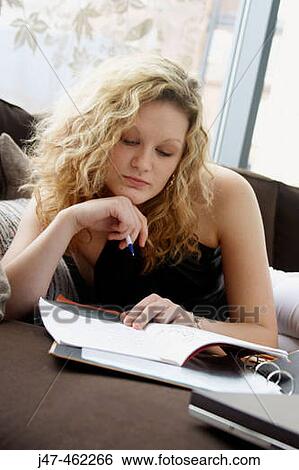 Stock Photograph - 20 year old girl sitting on the sofa, studying. Fotosearch