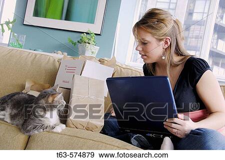 20 yr old woman home shopping on laptop computer looking at pet cat View Large Photo Image Stock Photo - 20 yr old woman home shopping on laptop computer looking at pet cat. Fotosearch
