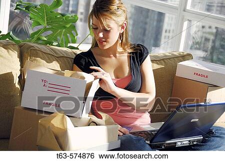 20 yr old woman looking into parcels after home shopping on laptop computer View Large Photo Image Stock Photograph - 20 yr old woman looking into parcels after home shopping on laptop computer. Fotosearch