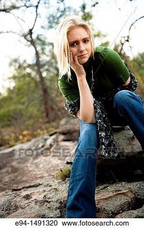 21 year old blond woman wearing green sweater and blue jeans sitting on a rock formation in the mountains. View Large Photo Image Stock Image - 21 year old blond woman wearing green sweater and blue jeans sitting on a rock formation in the mountains.. Fotosearch