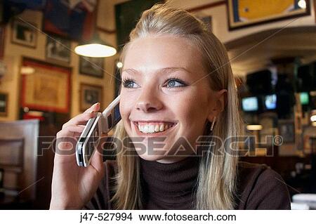 21 year old girl in a cafe on her mobile phone, smiling View Large Photo Image Picture - 21 year old girl in a cafe on her mobile phone, smiling. Fotosearch