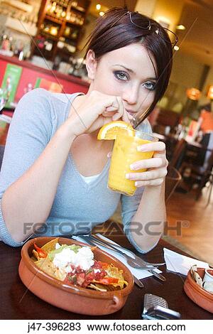 21 year old girl in restaurant eating nachos, drinking orange, smiling into camera View Large Photo Image Stock Image - 21 year old girl in restaurant eating nachos, drinking orange, smiling into camera. Fotosearch